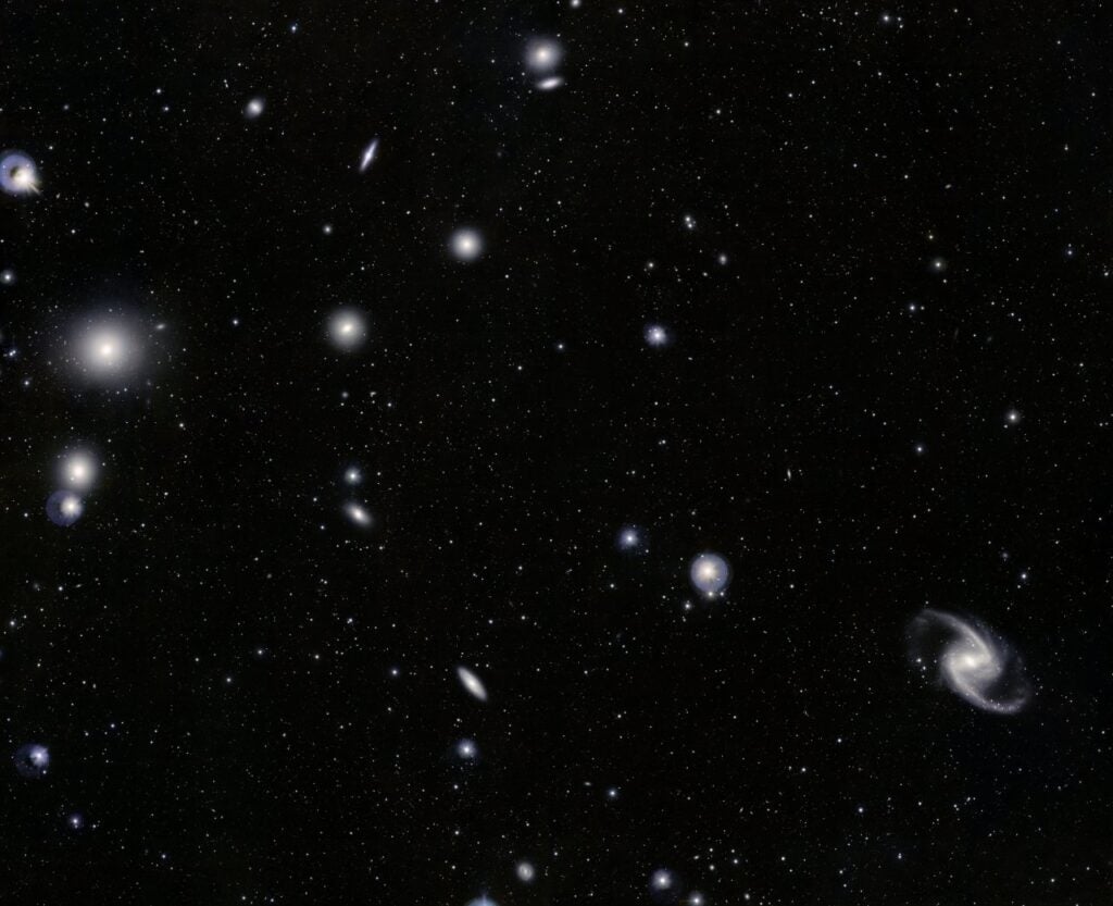 This cluster is one of the closest galaxy groups beyond the Local Group, of which the Milky Way is a part. At lower right is the elegant barred-spiral galaxy NGC 1365.