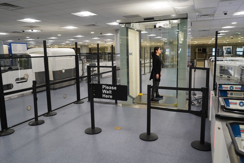 Woman standing in TSA self scan booth at airport