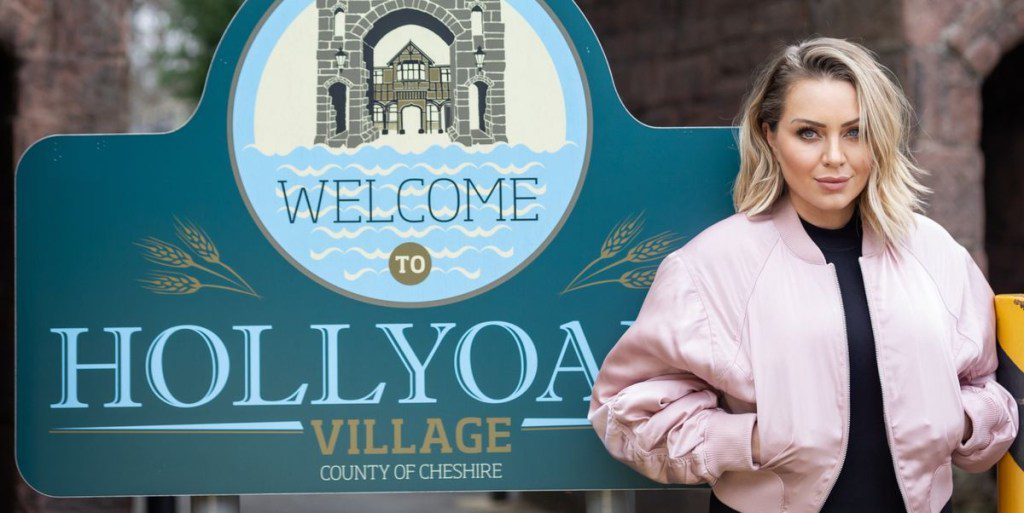 Rita Simons standing in front of the Hollyoaks sign