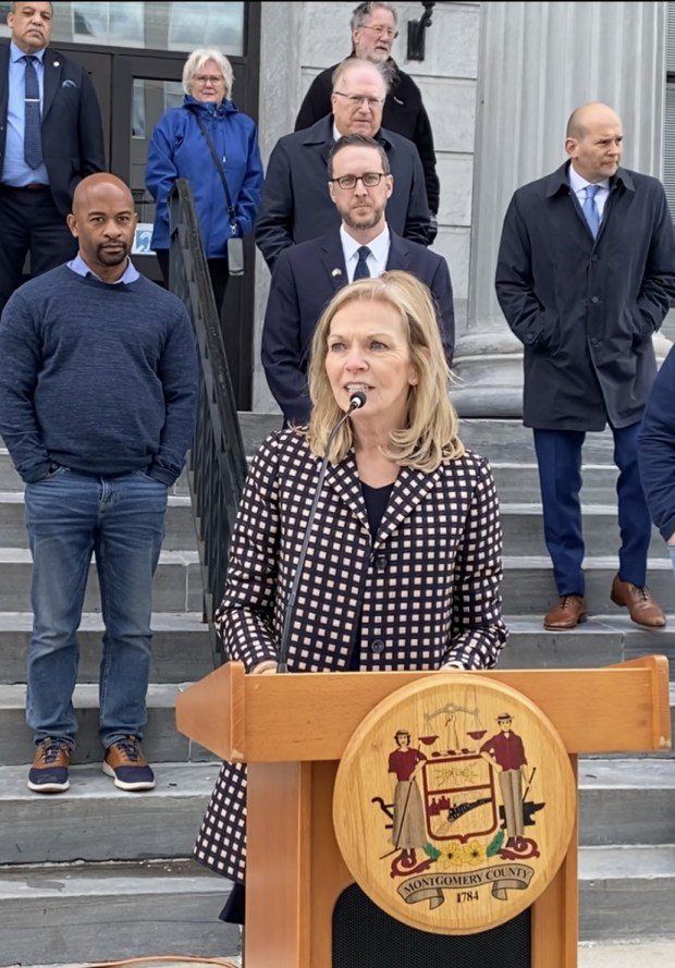 Woman standing outdoors at podium in front of courthouse steps