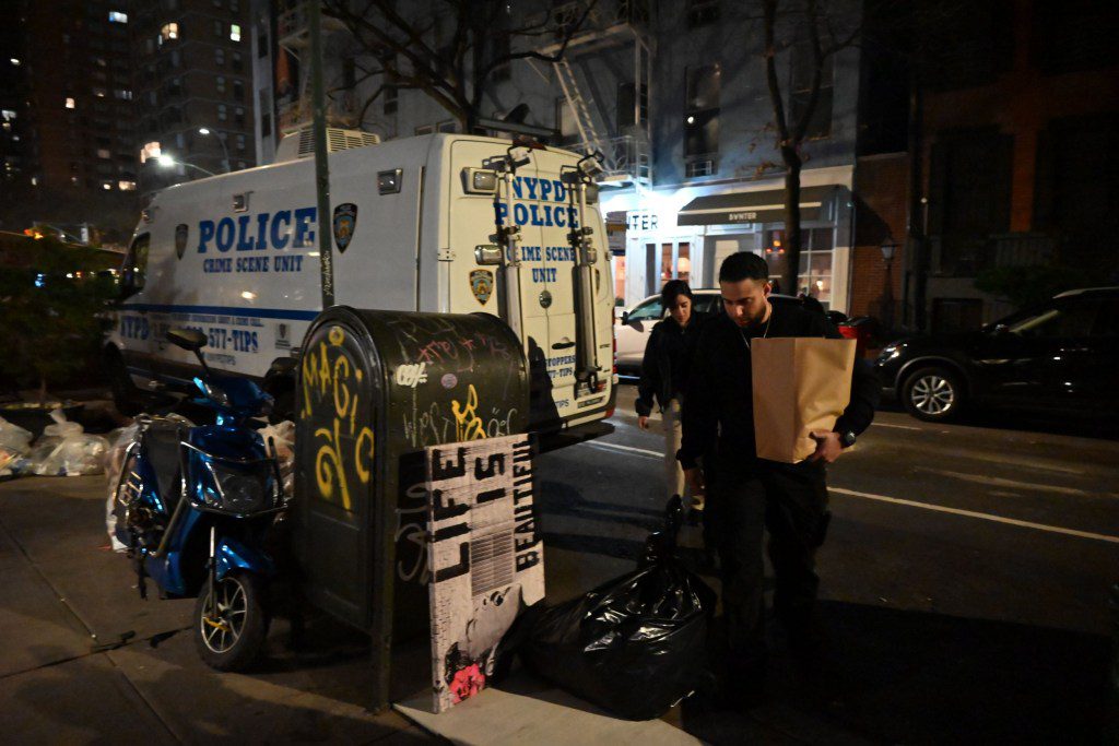 Investigators examining evidence bags at the crime scene in Manhattan, New York, on March 15 