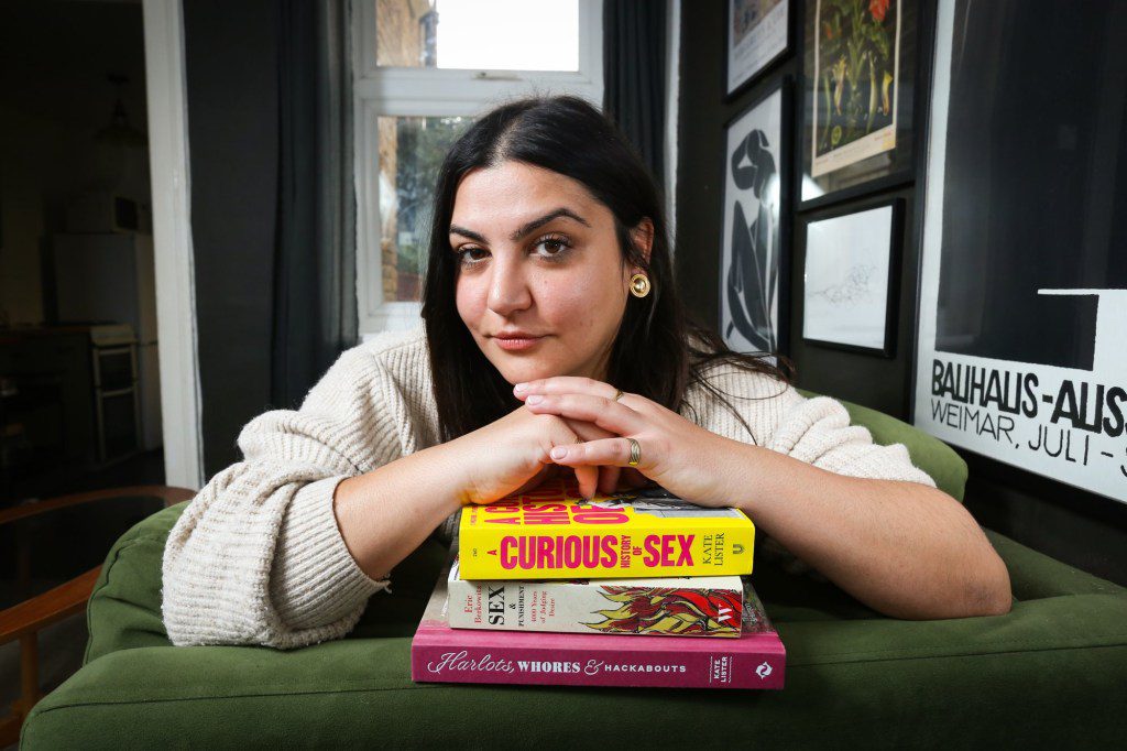 Almara Abgarian at home with her arms resting on a pile of books about sex