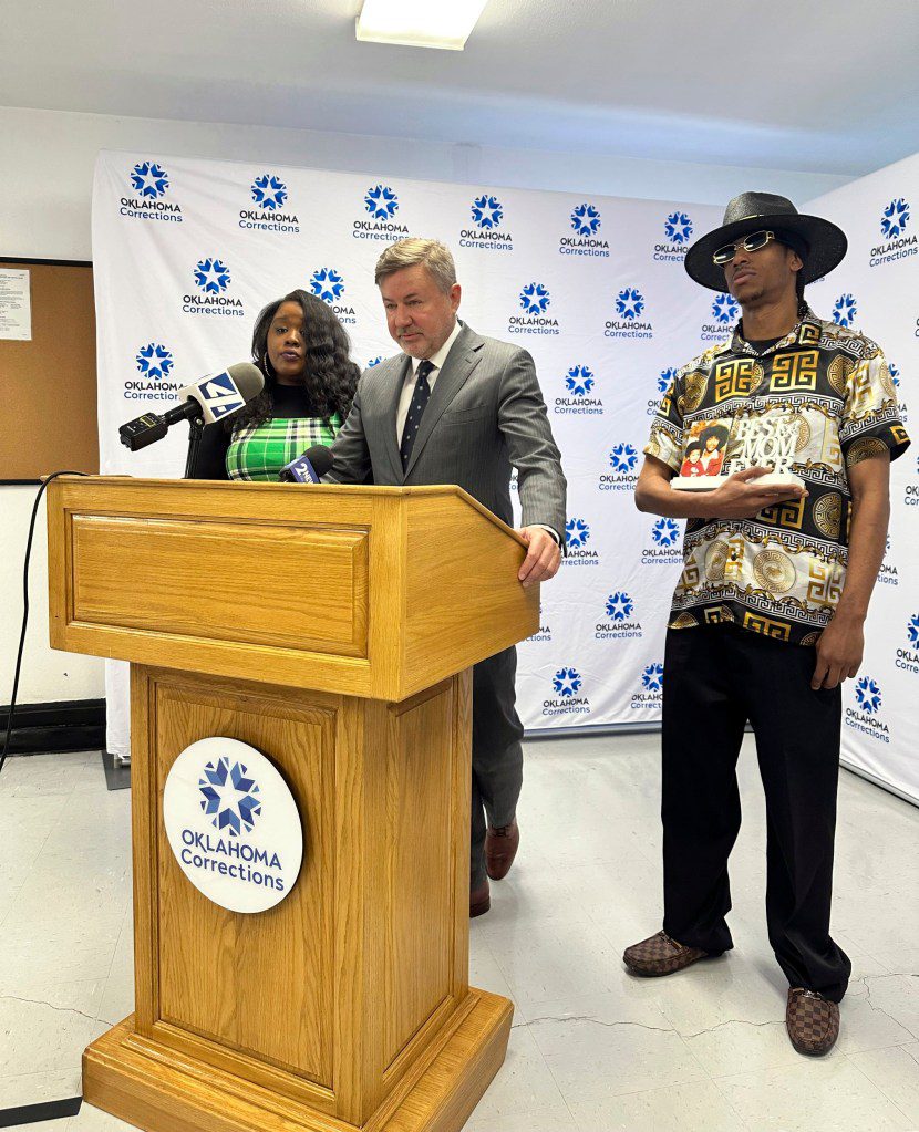 Oklahoma Attorney General Gentner Drummond reads a statement on behalf of murder victim Janet Moore on Thursday, April 4, 2024, while standing between Moore's son, Phillip Zachary, Jr., and niece Morgan Miller-Perkins.