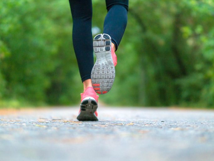 Running woman in the forest. Close-up of sneakers.