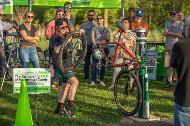 A guest holds a bike wheel at the dedication of a bicycle repair stand at Stony Creek Park on Thursday, May 2 2024. (Photo by James Short for North Penn Now)